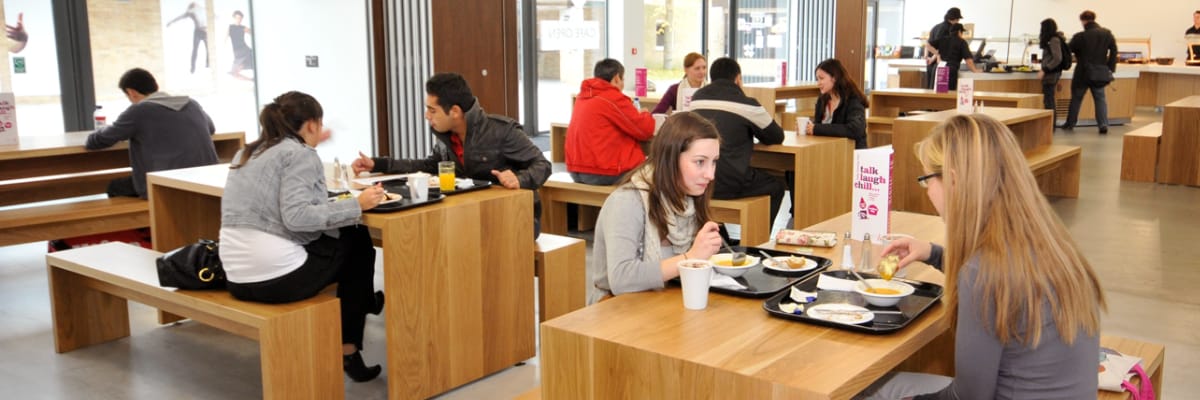 Students sit eating in a dining hall.