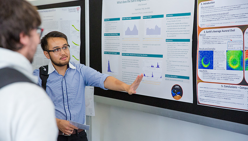 A male student presents his poster to another student