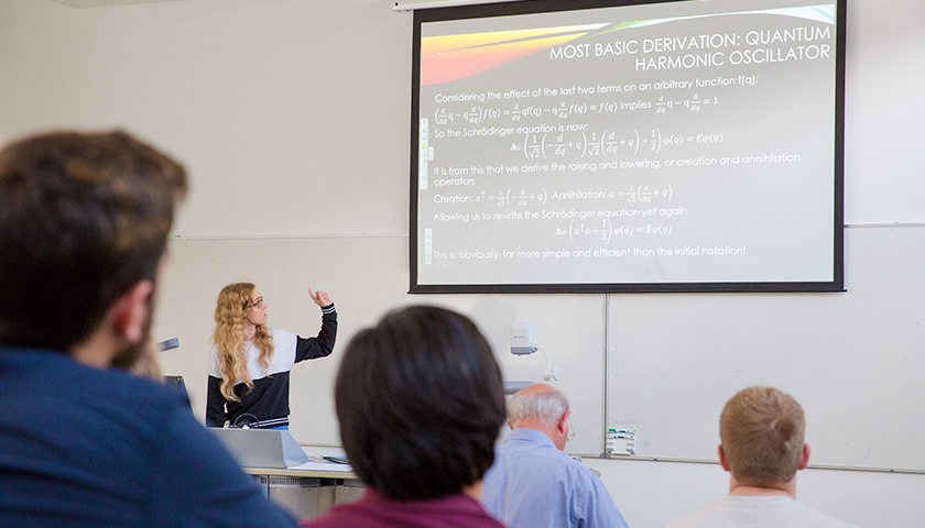 A female student presents a presentation to a lecture theatre of people