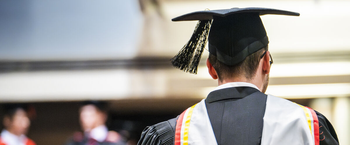 A graduate in cap and gown is pictured from the rear.