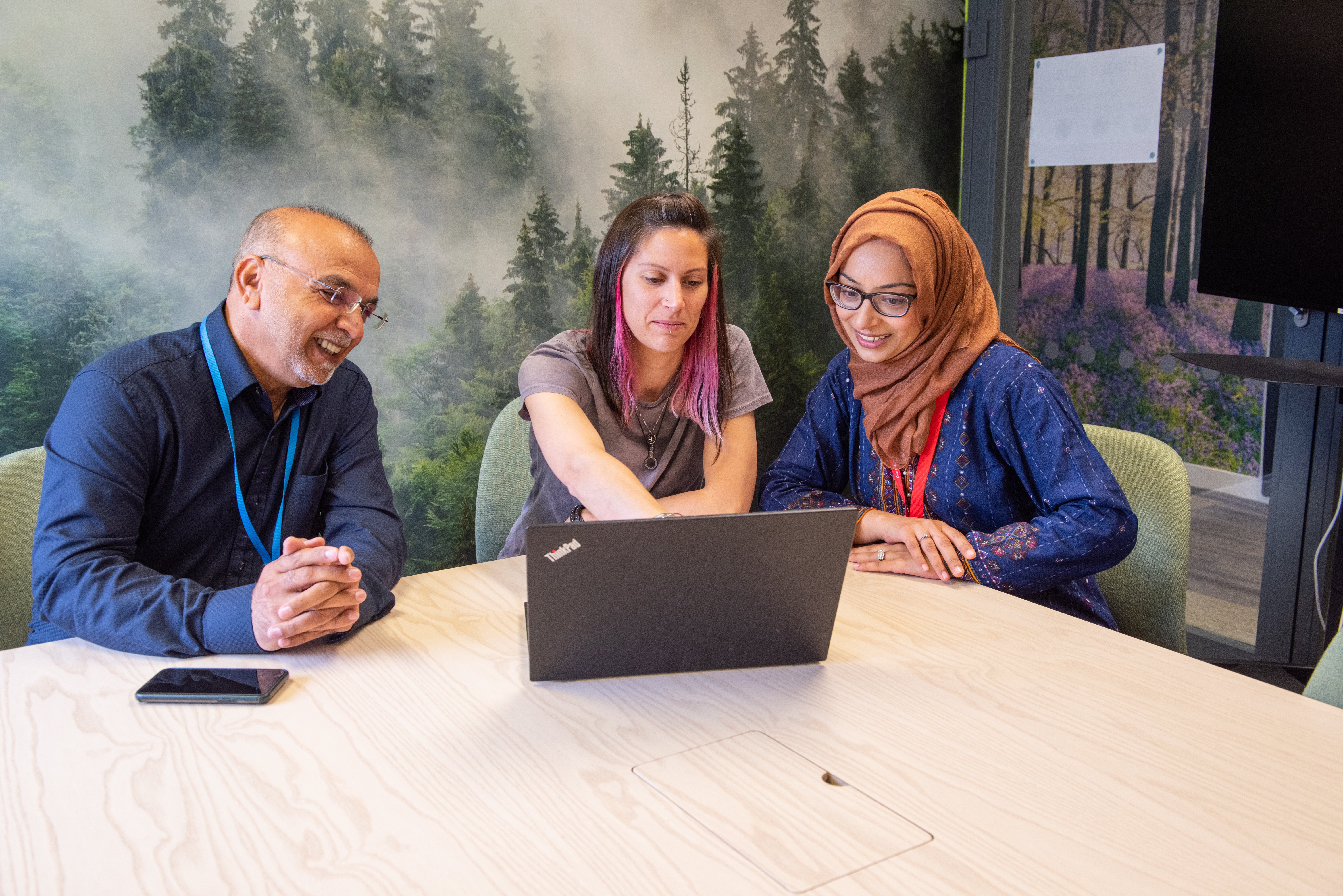 Staff gather around a laptop