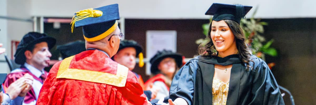 A student shakes hands with a dignitary as they receive their certificate.