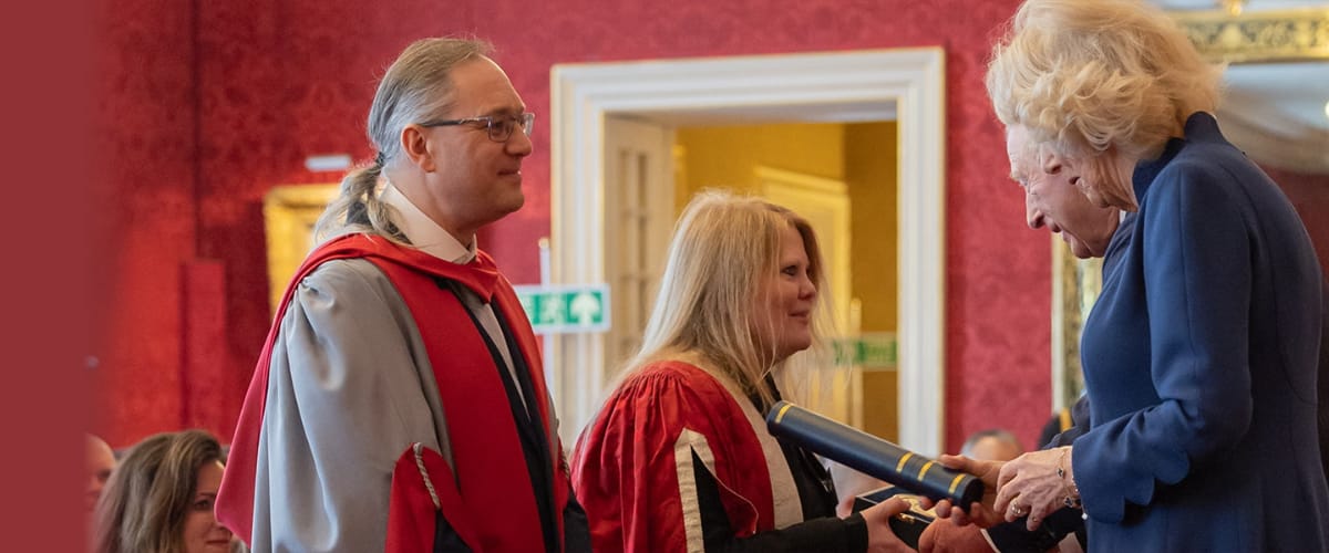 King Charles and Queen Camilla meet Lancaster University academics in a red room.