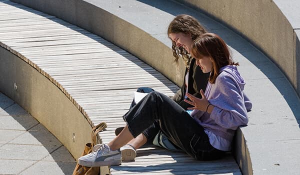 Students sitting outdoors on campus on a sunny day