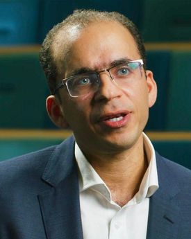 Head shot photo of Mahmoud Gad, he has short thinning black hair and wears glasses, he is talking.