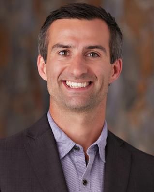 Head shot of Tibor Vegh, he has short cropped dark hair and a friendly smile.